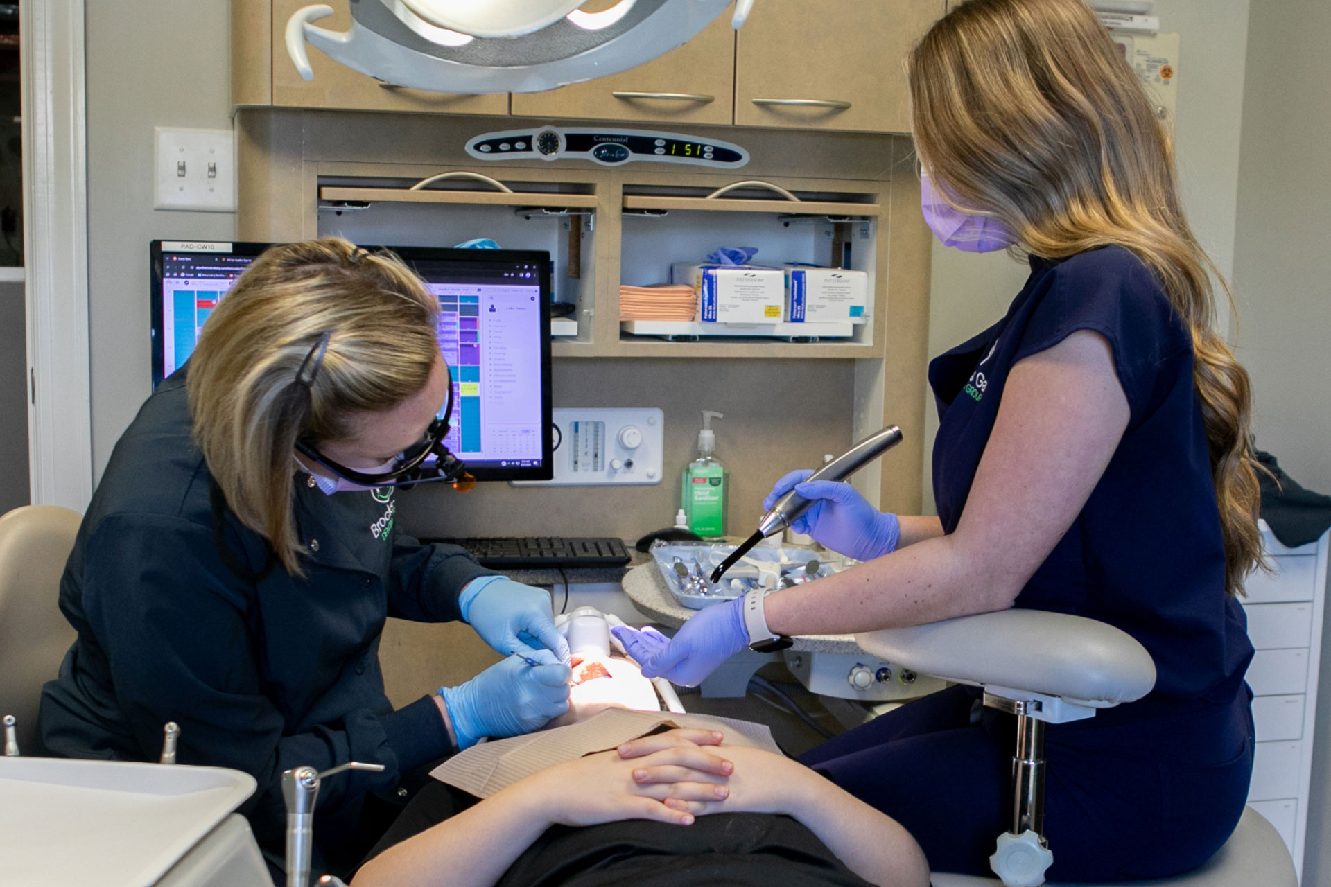 Dr. Sewel and assistant performing oral exam on patient